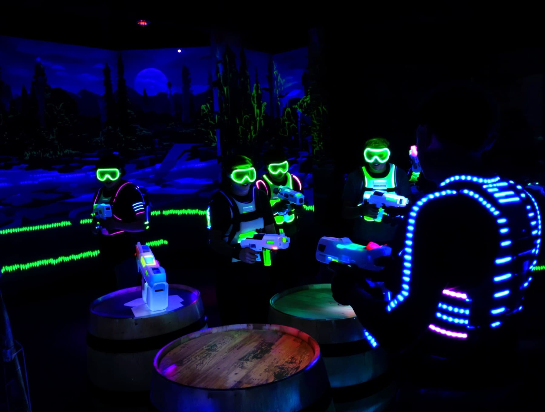 Players in safety goggles behind bunkers in a gel blaster arena